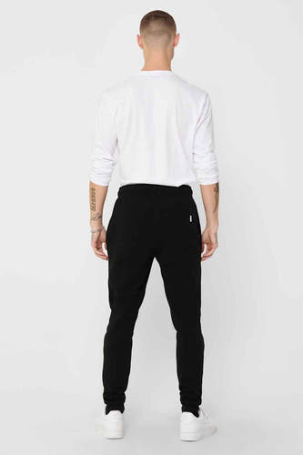 Zwarte joggingbroek van ONLY & SONS, achterkant gezien, met witte sneakers en wit shirt met lange mouwen.
