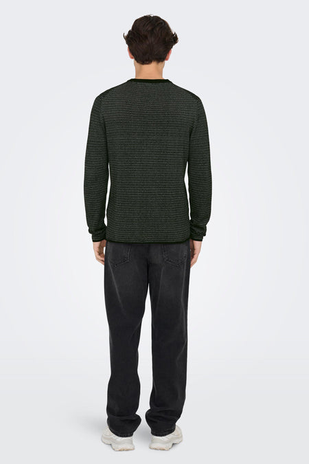 Pull noir à col rond de ONLY & SONS® avec de petits pois blancs, porté de dos avec un jean foncé et des baskets blanches