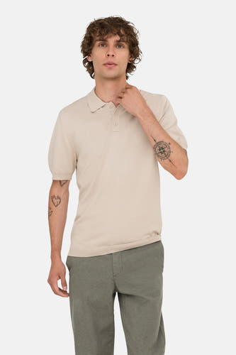 Pull-over beige de ONLY & SONS, avec des manches courtes, porté avec un pantalon vert olive et des tatouages sur les bras.