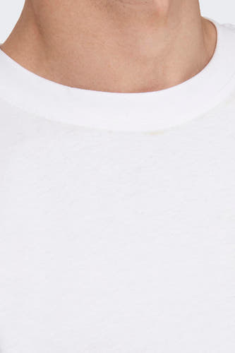 T-shirt blanc de ONLY & SONS®, porté avec un pantalon gris à carreaux et un bracelet rouge.