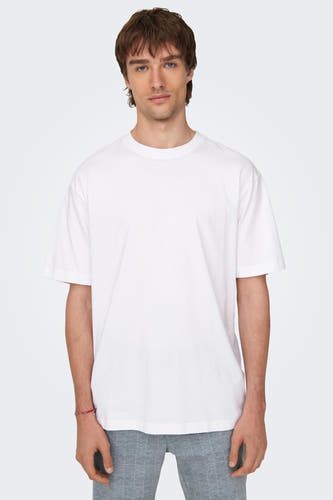 Wit T-shirt van ONLY & SONS®, gedragen met een grijze broek met ruitpatroon en een rode armband.
