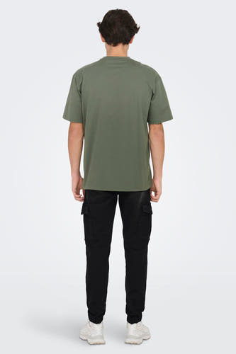 T-shirt vert de manteses courtes ONLY & SONS, vu vu de dos avec un pantalon noir et des baskets blanches.
