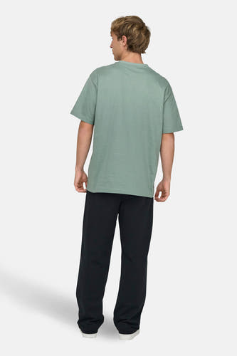 T-shirt vert de ONLY & SONS, vu de dos, associé à un pantalon noir et des chaussures blanches.
