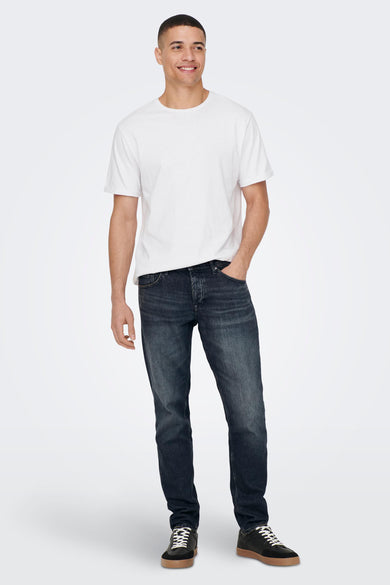Jean tapered en denim gris foncé de ONLY & SONS, porté avec un T-shirt blanc et des baskets noires.