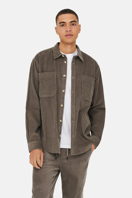 Chemise brune d'ONLY & SONS, à longues manches et poches sur la poitrine, portée sur un T-shirt blanc.