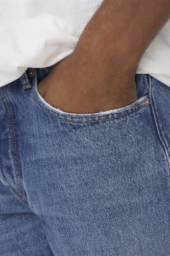 Jean large de denim bleu de ONLY & SONS, avec une main dans la poche.
