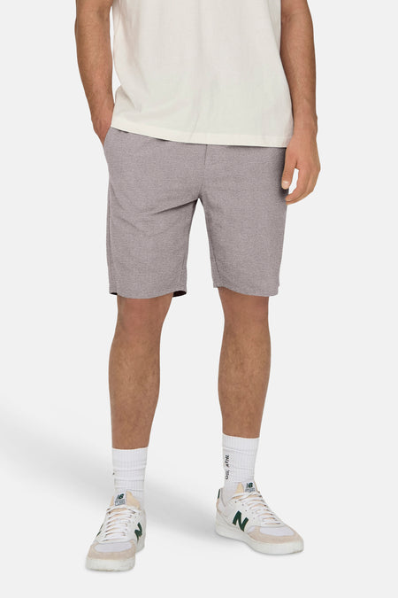 Short gris ONLY & SONS, avec poche arrière et chaussettes blanches et chaussures New Balance.