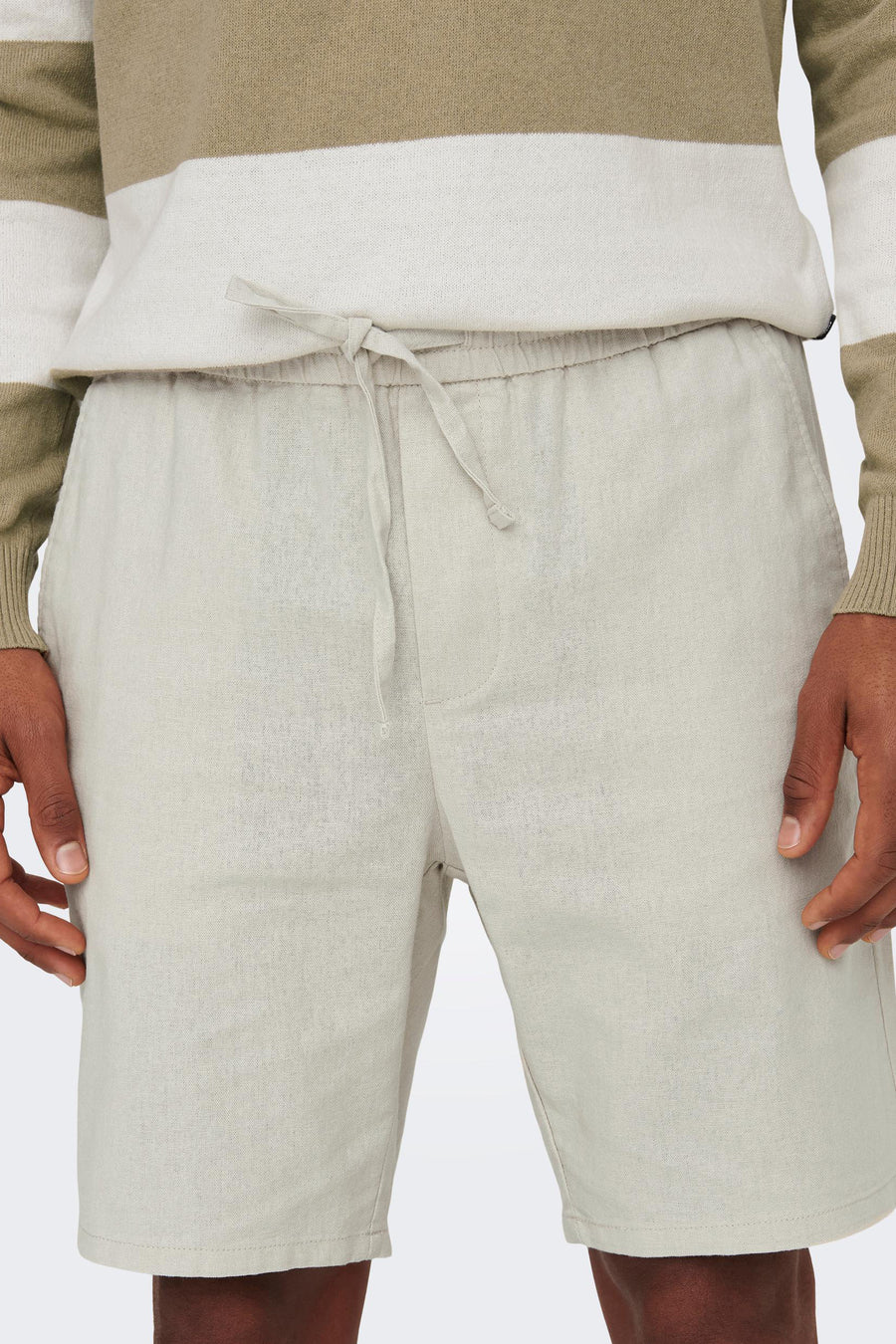 Licht beige linnen shorts met trekkoord, gedragen met een gestreepte trui.
