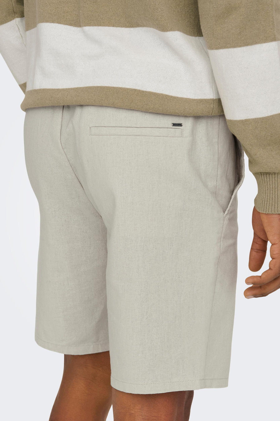 Beige shorts met achterzak en gestreept shirt.