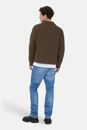 Blauwe straight jeans van ONLY & SONS, met lichte wassing, gecombineerd met een olijfgroen jasje en zwarte laarzen.
