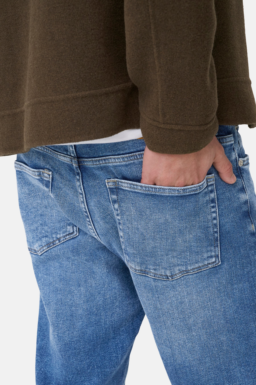 Jeans straight mid blue denim van ONLY & SONS, close-up achterkant, met hand in de zak, gecombineerd met groen jasje.
