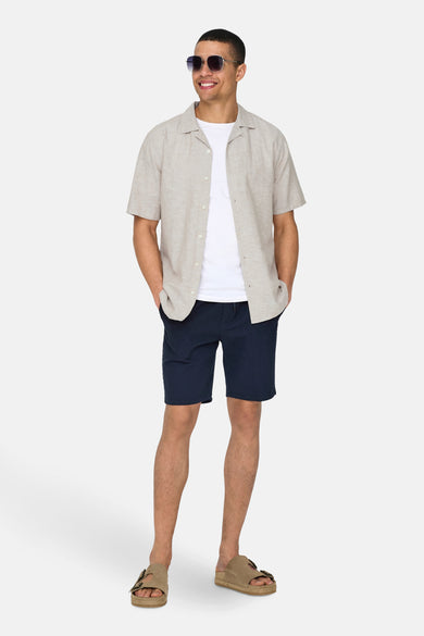 Chemise beige à manches courtes de ONLY & SONS, portée avec des shorts bruns et des baskets blanches.