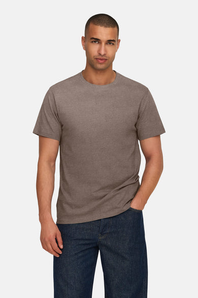 T-shirt marron à manches courtes de ONLY & SONS®, porté avec des jeans foncés et une main dans la poche.