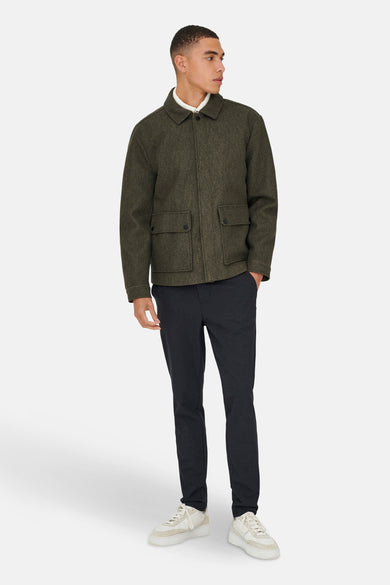 Bruine, korte jas van ONLY & SONS®, met zakken en gedragen over een wit overhemd en donkere broek.
