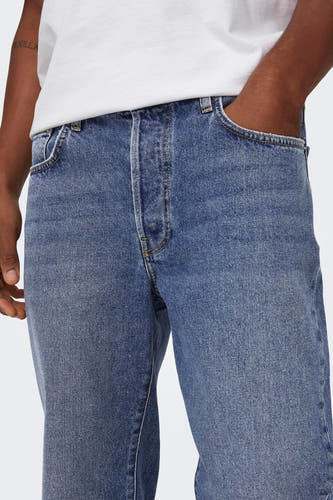 Jean en denim bleu marine large d'ONLY & SONS, avec une main dans la poche, associé à un T-shirt blanc.