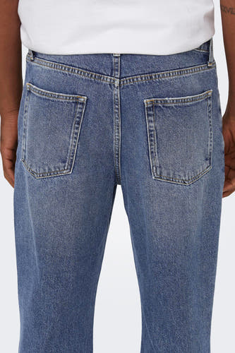 Jean en denim bleu mid, large de ONLY & SONS, avec des poches arrière et une chemise blanche.