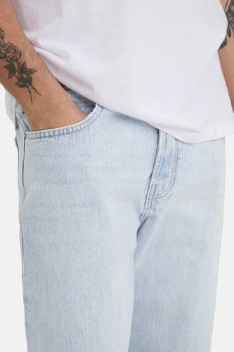 Jean droit bleu clair d'ONLY & SONS®, avec une main dans la poche et des tatouages visibles.