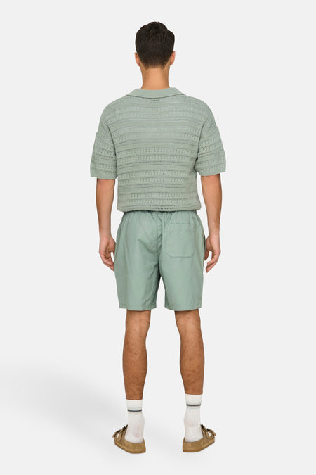 Pantalon court vert de ONLY & SONS, avec poche arrière, associé à des chaussettes et des sandales.