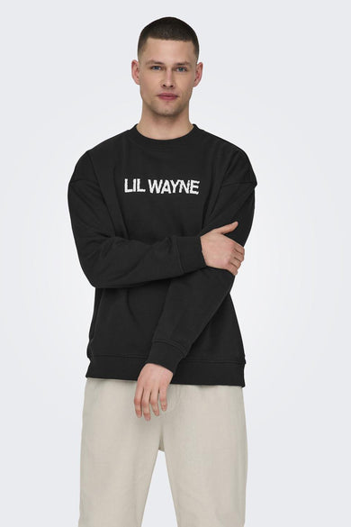 Pull-over noir à col rond de ONLY & SONS, avec "LIL WAYNE" dessus, associé à un pantalon beige.