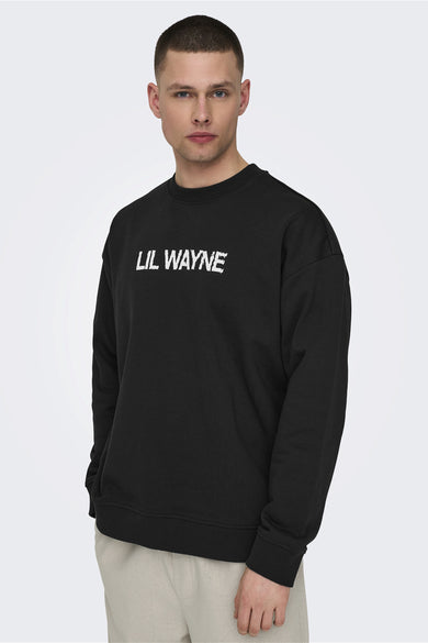 Pull-over noir d'ONLY & SONS avec une impression blanche "Lil Wayne" sur la poitrine, associé à un pantalon beige.