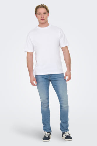 Jean slim en denim bleu clair de ONLY & SONS®, porté avec un T-shirt blanc et des baskets noires.