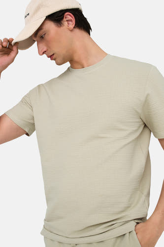 T-shirt beige à manches courtes de ONLY & SONS®, avec une texture à carreaux et porté avec un chapeau.