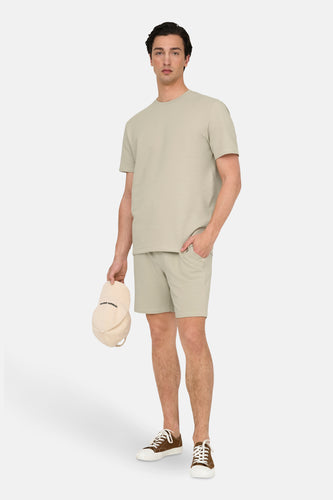 Man in een bijpassende waffle-knit set en bruine sneakers.