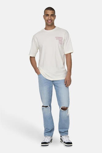 T-shirt beige à manches courtes de ONLY & SONS®, avec une petite impression sur la poitrine, associé à des jeans déchirés et des baskets.
