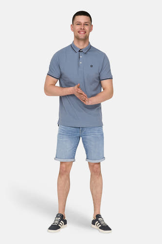 Mid blue denim jeansshort van ONLY & SONS, met opgerolde pijpen en gecombineerd met een blauw polo shirt en sneakers.
