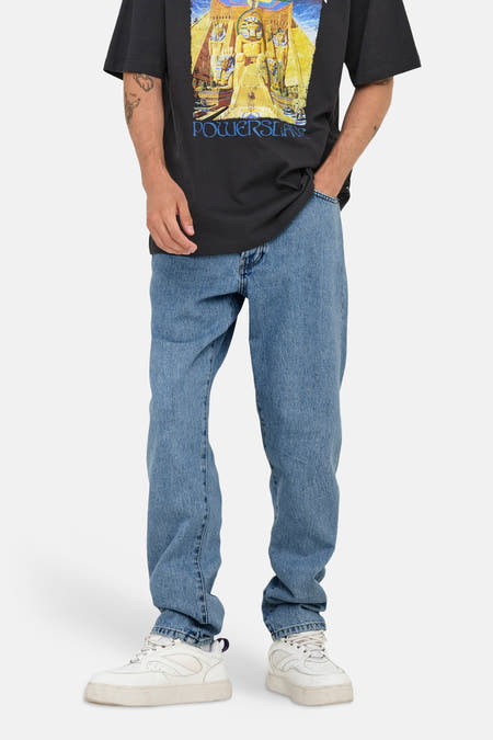 Lichtblauwe tapered jeans van ONLY & SONS®, met licht vervaagde plekken en gedragen met een zwart T-shirt en witte sneakers.