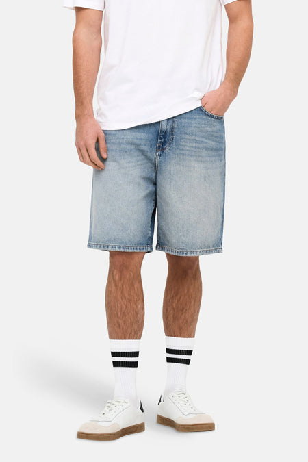 Short en jean en denim bleu moyen de ONLY & SONS®, porté avec un t-shirt blanc et des chaussettes rayées.