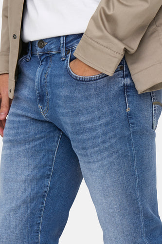 Blauwe spijkerbroek met beige jas.