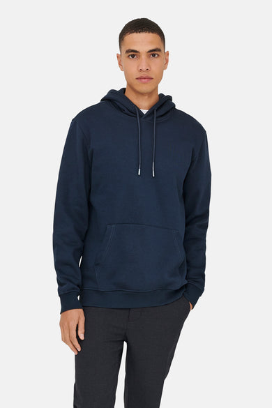 Pull-over bleu avec capuche de ONLY & SONS, avec des cordons et un sac à dos, porté avec un pantalon foncé.