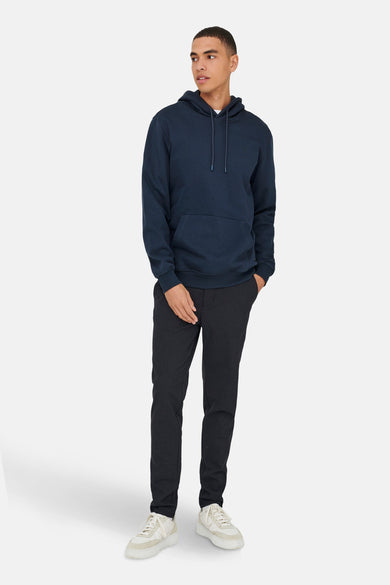 Pull-over bleu avec capuche de ONLY & SONS®, associé à un pantalon foncé et des baskets blanches.