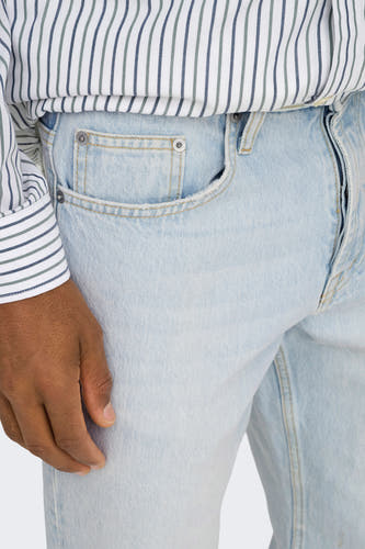 Jean droit en denim bleu clair d'ONLY & SONS®, avec un chemisier rayé et une main.
