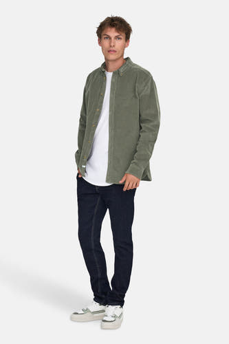Chemise verte à manches longues de ONLY & SONS, portée sur un T-shirt blanc et des jeans foncés, avec des sneakers blanches.