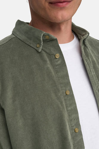 Chemise verte à manches longues de ONLY & SONS, texture corduroy, portée sur un T-shirt blanc avec une chaîne d'argent.