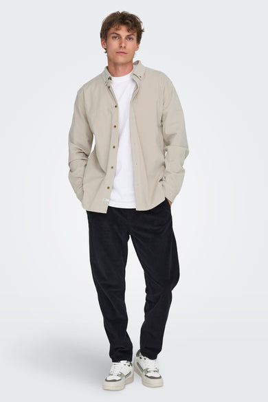Chemise écru de ONLY & SONS® à manches longues, portée sur un T-shirt blanc, avec un pantalon corduroy foncé et des baskets.