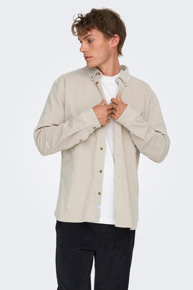 Chemise écru à manches longues de ONLY & SONS, avec fermeture à boutons, portée sur un T-shirt blanc et un pantalon noir.