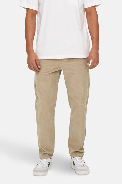 Pantalon beige ONLY & SONS® avec une texture corduroy et des sneakers blanches.