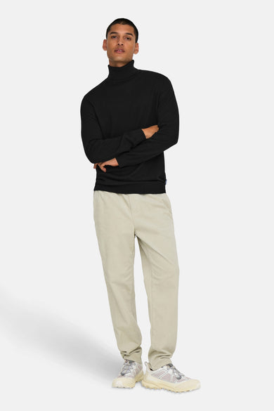 Pull-over noir avec col montant d'ONLY & SONS, porté avec un pantalon beige en corduroy et des baskets blanches.
