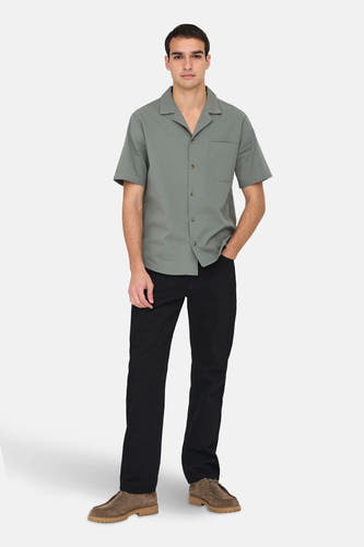 T-shirt kaki à manches courtes de ONLY & SONS®, avec une subtile texture, porté avec un pantalon noir et des chaussures en cuir.