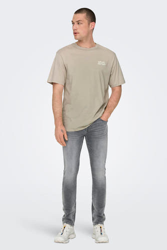 Jean slim fit en denim gris moyen de ONLY & SONS, avec une légère décoloration et des baskets blanches.