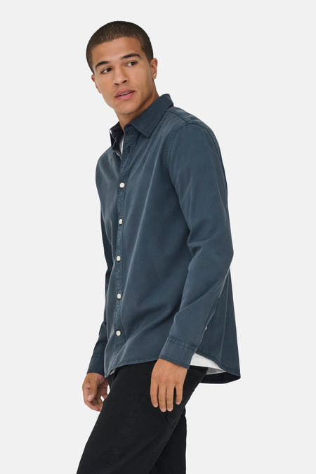 Chemise bleue à manches longues de ONLY & SONS®, portée avec un T-shirt blanc, un pantalon noir et des bottes.
