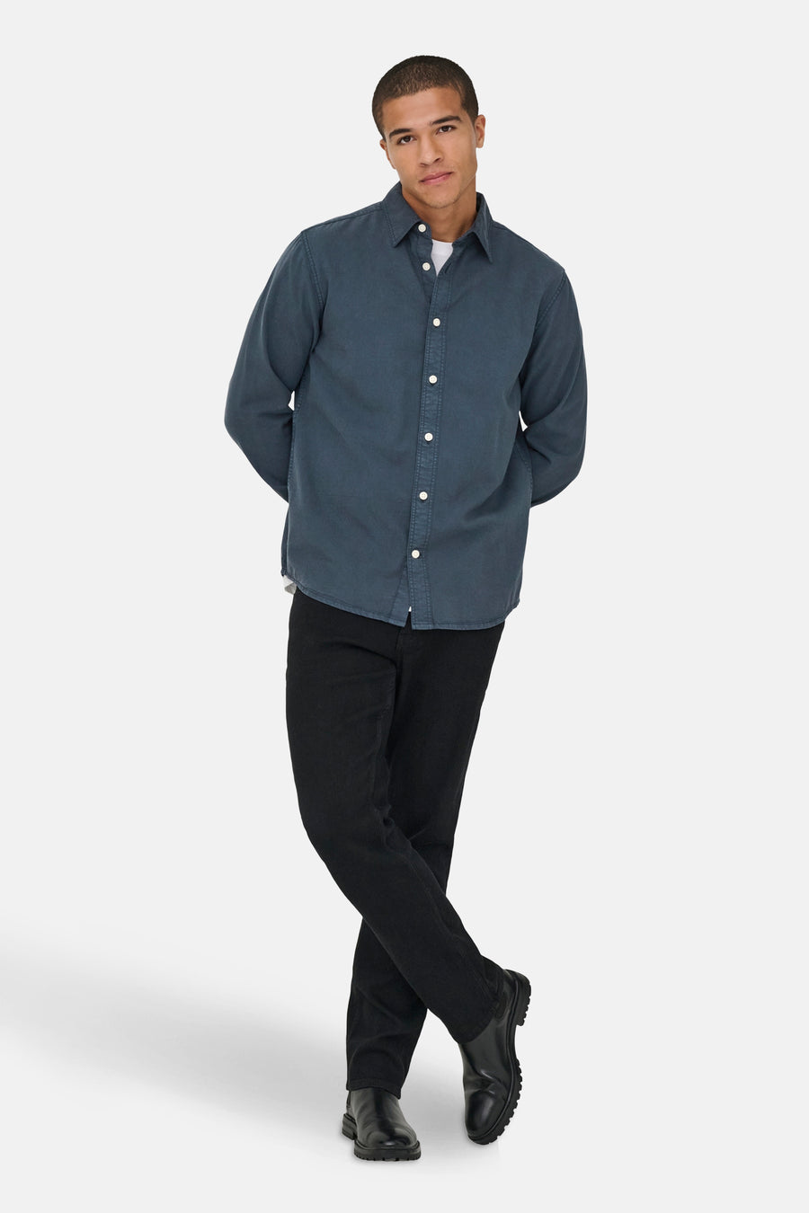 Man met een blauw overhemd, zwarte broek en laarzen.