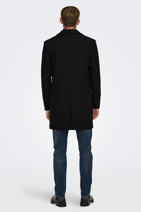 Veste longue noire d'ONLY & SONS, à motif uni, portée sur un pantalon de cuir noir et des chaussures noires, vue arrière.