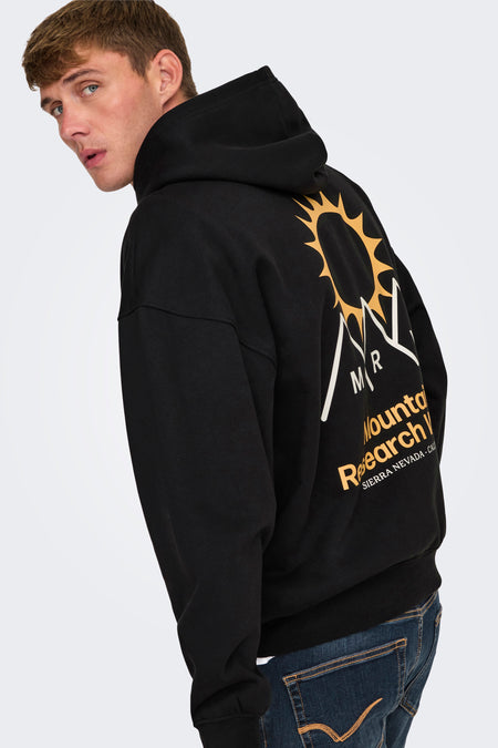 Pull-over noir avec capuche ONLY & SONS®, associé à des jeans foncés et des bottes noires.