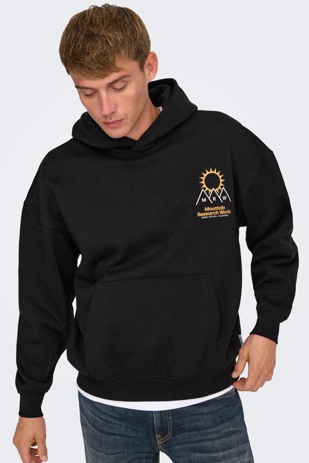 Pull-over noir avec capuche d'ONLY & SONS, imprimé sur la poitrine, porté sur un T-shirt blanc et des jeans bleus.
