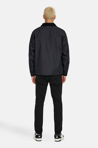 Manteau court noir d'ONLY & SONS® avec un col en corduroy, vu de l'arrière, associé à des jeans noirs et des baskets.