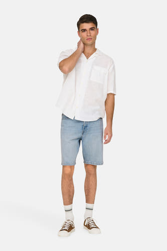 Lichtblauwe denim jeansshort van ONLY & SONS, met een onafgewerkte zoom, gedragen met een wit linnen shirt en bruine schoenen.

